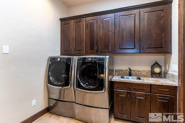 laundry room featuring cabinets, light tile patterned floors, washing machine and clothes dryer, and sink