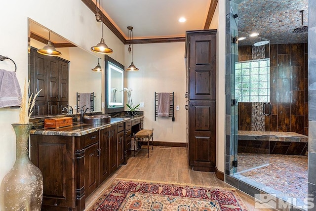 bathroom with wood-type flooring, vanity, a shower with shower door, and crown molding