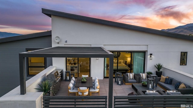 back house at dusk featuring an outdoor living space, a patio area, and a mountain view