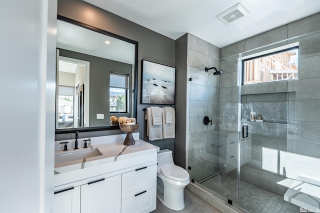 bathroom featuring tile patterned flooring, vanity, a shower with shower door, and toilet