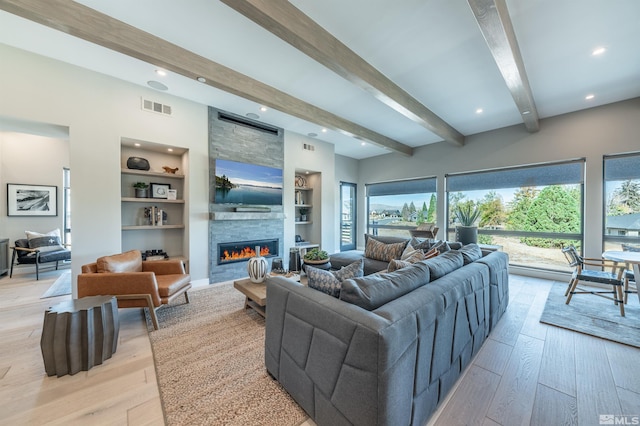 living room featuring beam ceiling, a fireplace, built in features, and light hardwood / wood-style floors