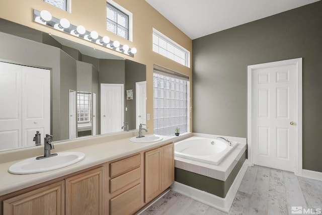 bathroom featuring hardwood / wood-style floors, vanity, and tiled bath