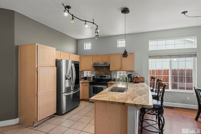 kitchen featuring light brown cabinets, sink, kitchen peninsula, decorative light fixtures, and appliances with stainless steel finishes