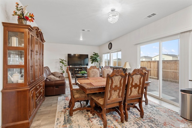 dining room with light hardwood / wood-style floors and an inviting chandelier