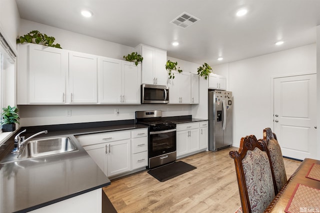 kitchen with stainless steel appliances, white cabinetry, light hardwood / wood-style floors, and sink