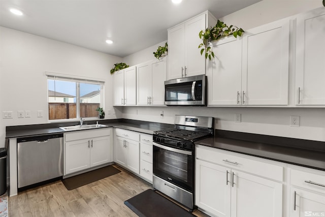 kitchen featuring white cabinets, sink, appliances with stainless steel finishes, and light hardwood / wood-style flooring