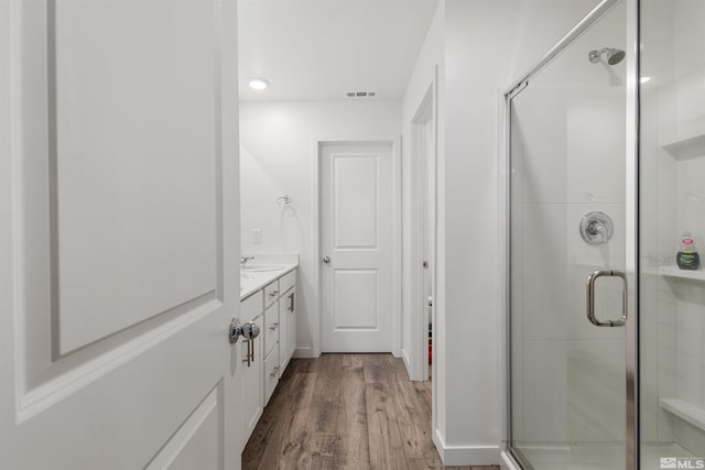 bathroom with vanity, hardwood / wood-style flooring, and a shower with shower door