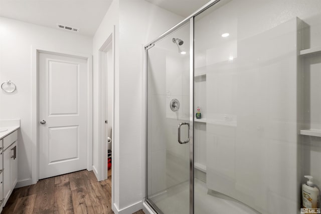 bathroom with vanity, hardwood / wood-style flooring, and a shower with door