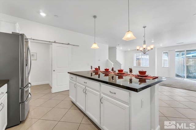 kitchen featuring stainless steel refrigerator, light tile patterned floors, a kitchen island, pendant lighting, and white cabinets