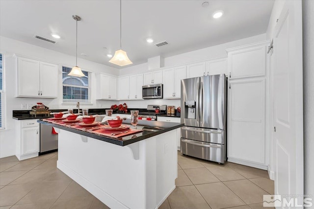 kitchen with a kitchen island, decorative light fixtures, a breakfast bar, white cabinets, and appliances with stainless steel finishes