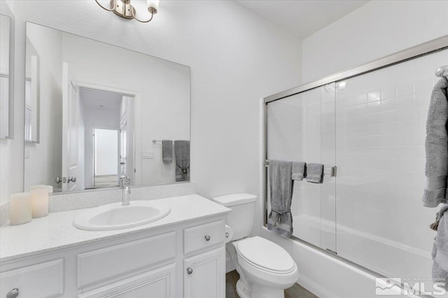 full bathroom featuring combined bath / shower with glass door, vanity, and toilet