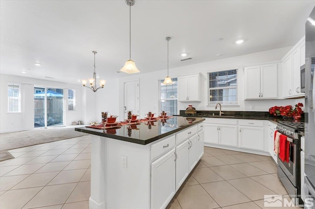 kitchen with decorative light fixtures, a kitchen island, plenty of natural light, and stainless steel range with gas cooktop