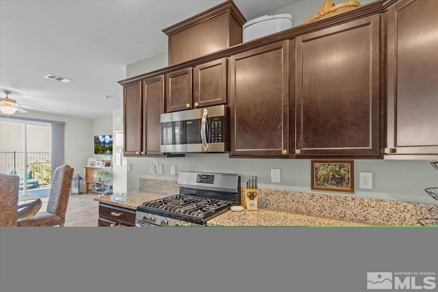 kitchen with light stone countertops, appliances with stainless steel finishes, dark brown cabinetry, and ceiling fan