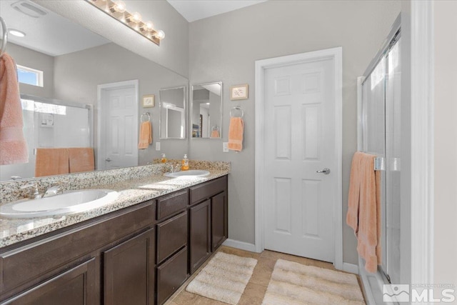 bathroom with tile patterned floors, a shower with door, and vanity