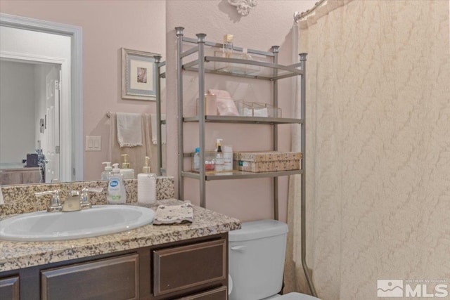 bathroom featuring a shower with curtain, vanity, and toilet