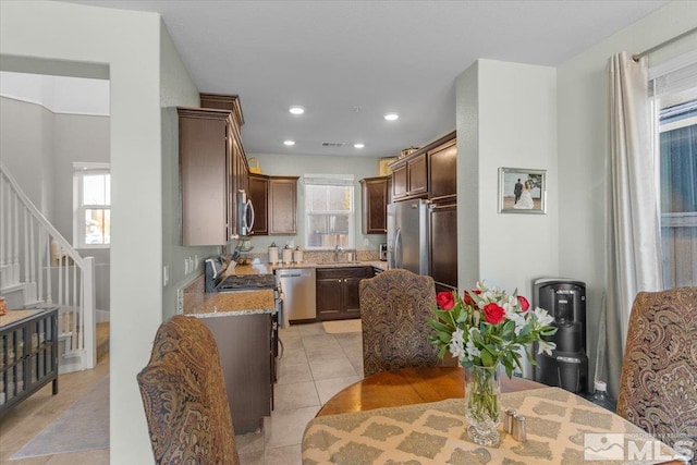 kitchen with appliances with stainless steel finishes, sink, light stone counters, and light tile patterned flooring