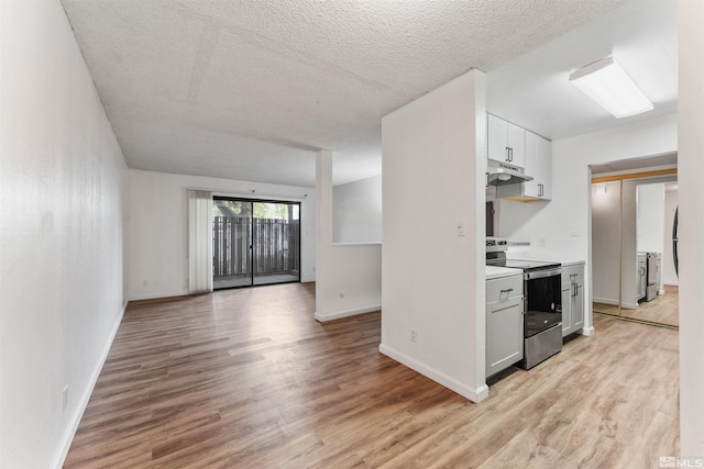 kitchen with light wood-type flooring, a textured ceiling, electric range, and white cabinetry