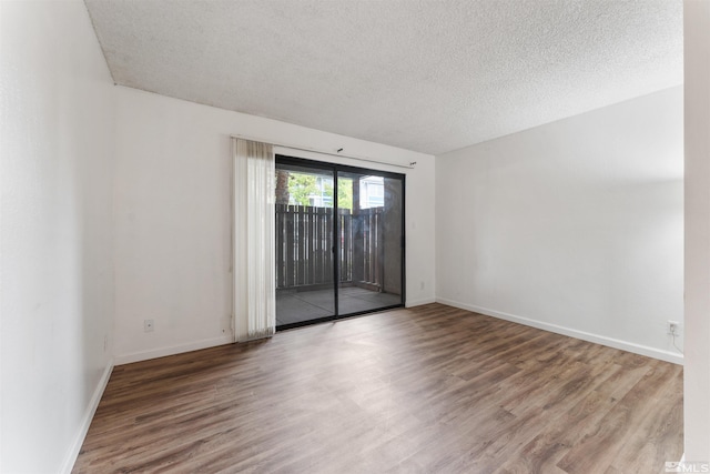 empty room with hardwood / wood-style floors and a textured ceiling