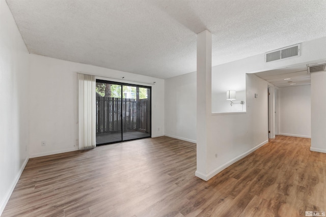 spare room featuring hardwood / wood-style flooring and a textured ceiling