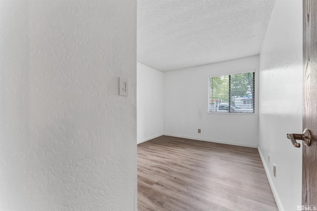 unfurnished room with light hardwood / wood-style floors and a textured ceiling