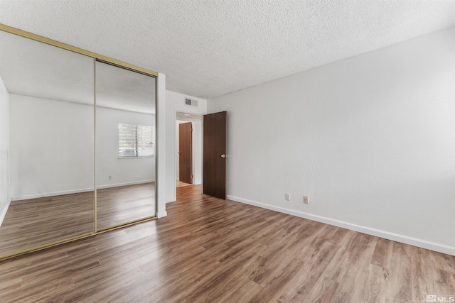 unfurnished bedroom featuring a textured ceiling, hardwood / wood-style flooring, and a closet