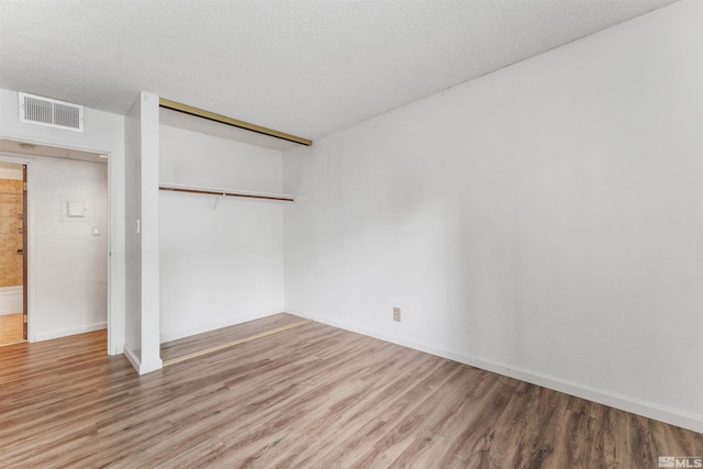 spare room featuring hardwood / wood-style flooring and a textured ceiling