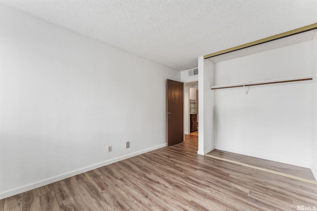 unfurnished bedroom featuring a closet, a textured ceiling, and hardwood / wood-style flooring