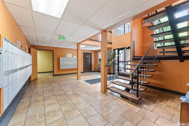 interior space with tile patterned flooring, a drop ceiling, and a mail area