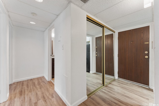 hall featuring light wood-type flooring and a drop ceiling