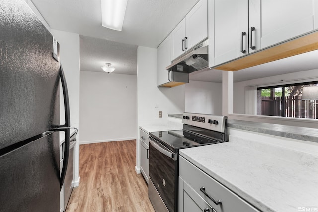 kitchen featuring white cabinetry, stainless steel electric range oven, black refrigerator, and light hardwood / wood-style flooring