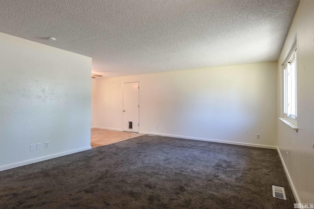 empty room with carpet floors and a textured ceiling