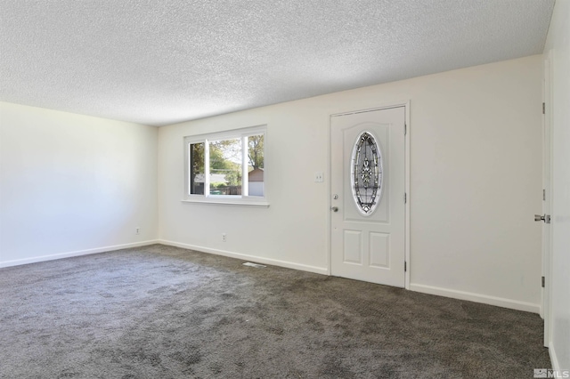 foyer entrance with dark carpet and a textured ceiling