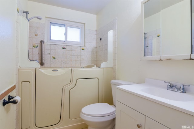 bathroom with vanity, a tub to relax in, and toilet