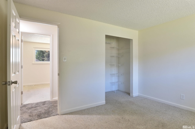 unfurnished bedroom featuring light colored carpet, a textured ceiling, and a closet