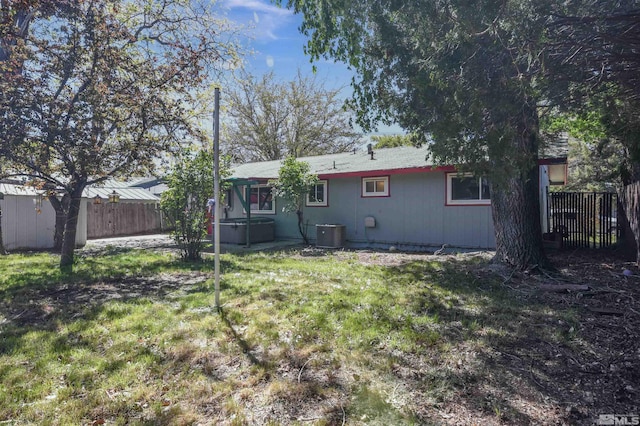 back of property featuring a jacuzzi, a yard, and central AC