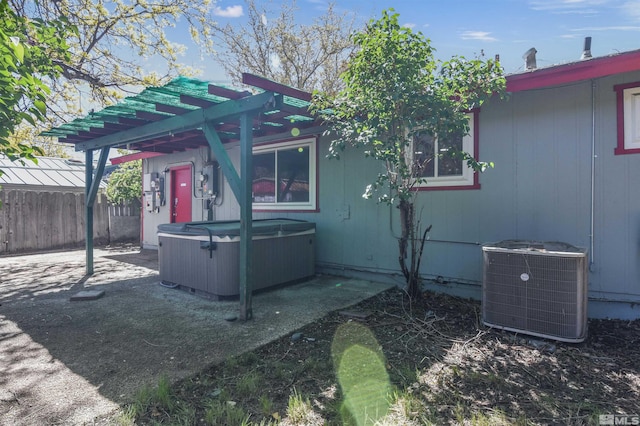 view of home's exterior featuring central AC, a pergola, and a hot tub