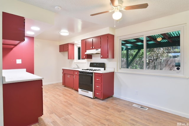 kitchen featuring ceiling fan, light hardwood / wood-style floors, a textured ceiling, and gas range gas stove