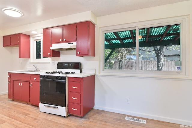 kitchen featuring light hardwood / wood-style floors, white range with gas stovetop, and sink