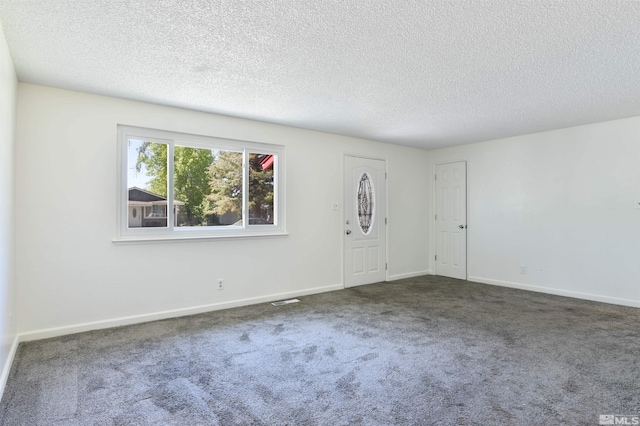 interior space with a textured ceiling and dark carpet