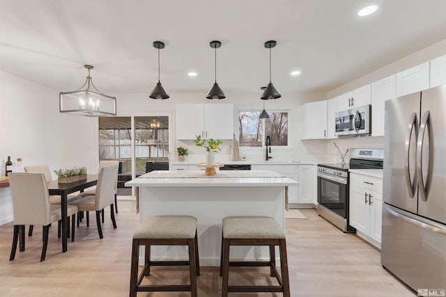 kitchen featuring decorative light fixtures, a center island, stainless steel appliances, and plenty of natural light