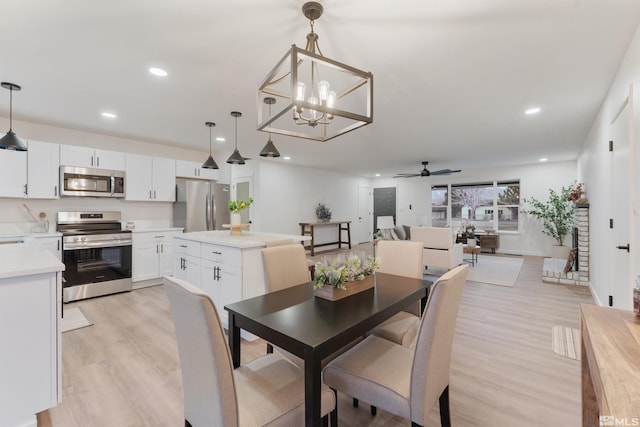 dining space with ceiling fan with notable chandelier and light wood-type flooring