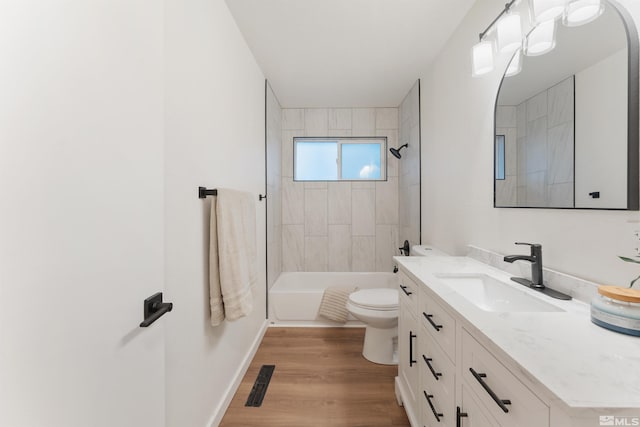 full bathroom featuring tiled shower / bath, toilet, vanity, and hardwood / wood-style flooring