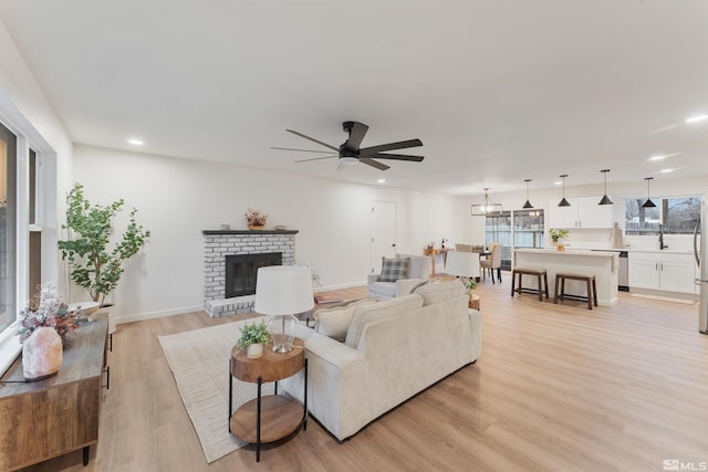 living room featuring a fireplace, light hardwood / wood-style floors, and ceiling fan