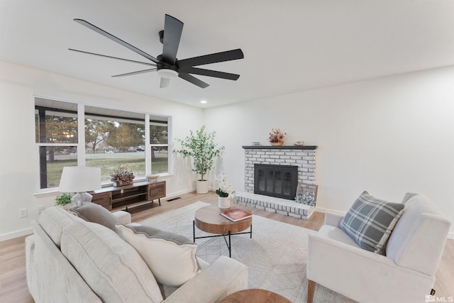 living room featuring ceiling fan, light hardwood / wood-style floors, and a fireplace