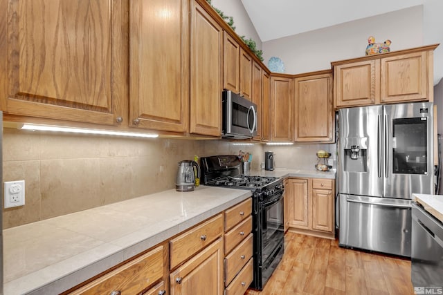 kitchen featuring tasteful backsplash, light hardwood / wood-style flooring, stainless steel appliances, and vaulted ceiling