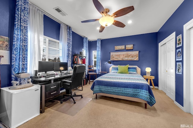 bedroom with a closet, white refrigerator, light colored carpet, and ceiling fan