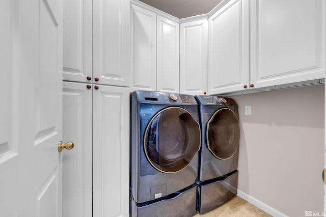 washroom with washer and dryer and cabinets