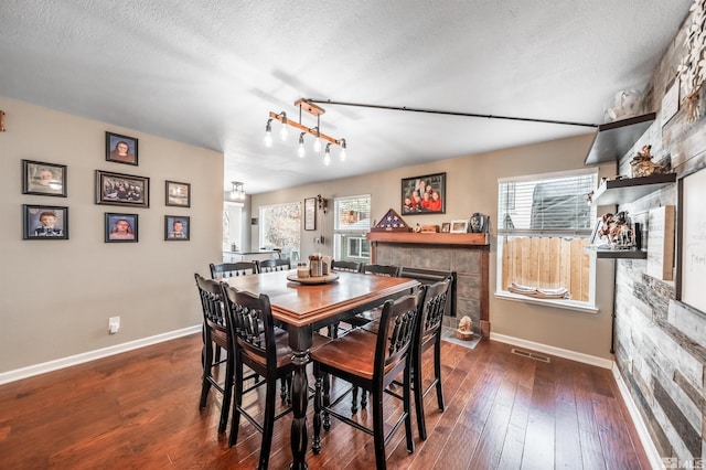 dining space featuring a tile fireplace, dark hardwood / wood-style flooring, and a textured ceiling