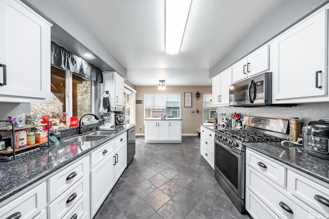 kitchen with white cabinetry, sink, dark stone counters, and appliances with stainless steel finishes