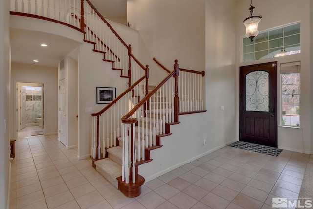 entrance foyer featuring light tile patterned floors and a towering ceiling